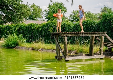 Two children ready jump from the bridge into the lake.