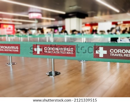 Green ribbon barrier inside an airport with the warning of travel restrictions due to the worlwide spread of Coronavirus