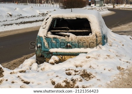 a wrecked car on the side of the road littered with a mountain of snow. background picture.