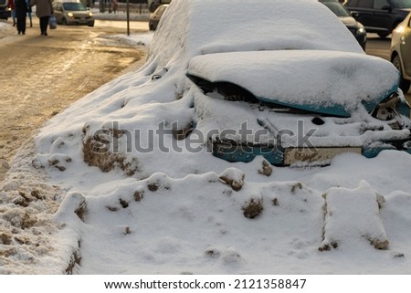 a broken car under the snow. a snowdrop by the side of the road. background picture.