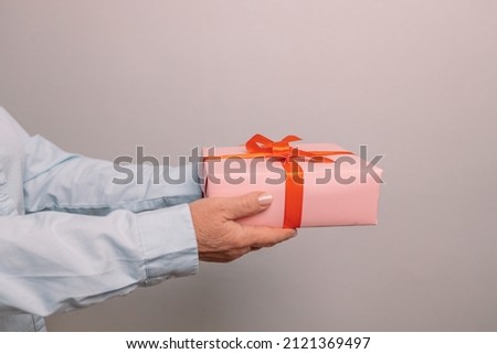 Close up shot of woman hands holding surprise gift package box on pastel background with copy space. Valentine's gift