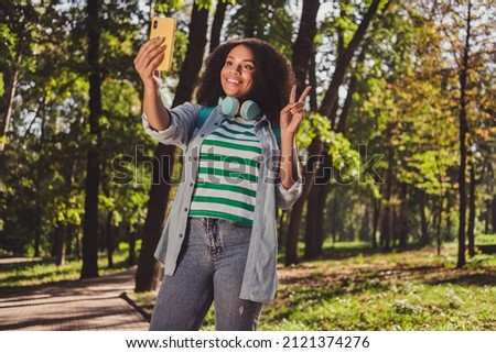 Photo of young african lovely lady use cellphone vacation make selfie picture show fingers peace v-symbol outdoors