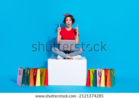 Full body photo of young excited woman point fingers empty space recommend shopping laptop isolated over blue color background