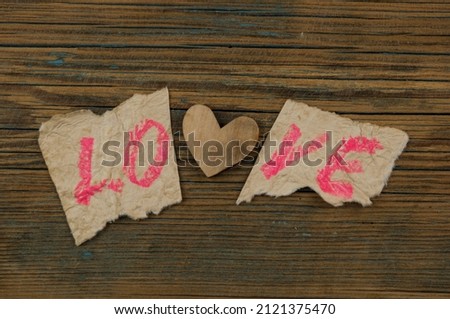 Word LOVE written on torn paper on wood background