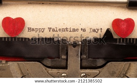 Happy Valentine`s day - phrase on typewriter. Valentines Day greetings concept. Little red wooden heart close up. Valentines greeting card.