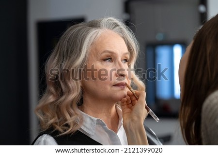 Beautiful elderly woman getting make-up in a beauty salon Royalty-Free Stock Photo #2121399020