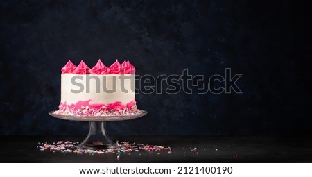 Pink and white Birthday Cake on dark background.