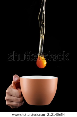 Egg Yolk dripping, falling in to cup, on black background.