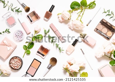 Bright spring composition with assortment of decorative cosmetic products on white background with aromatic roses and eucalyptus leaves top view. Spring cosmetic sale and promo banner.