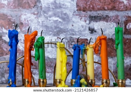 Candlestick with multi-colored candles on the background of a brick wall close-up.