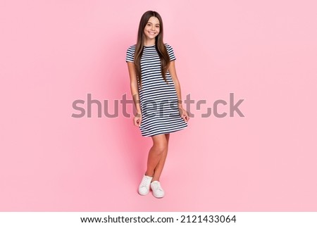 Photo of shiny charming girl dressed striped dress walking smiling isolated pink color background