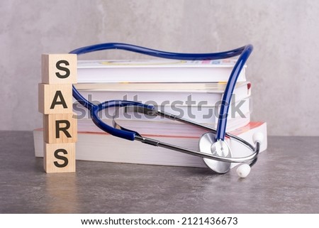 word sars is written on wooden cubes near a stethoscope on a gray background. medical concept for hospital, clinic and medical business. concept of medical education with book and stethoscope