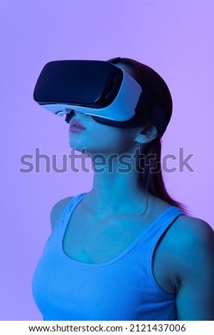 Portrait of a woman wearing virtual reality glasses. Vertical image. Neon lighting.