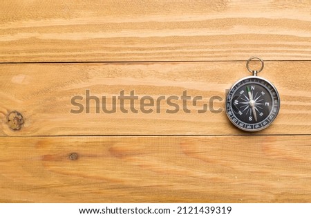 Old compass on wooden background.