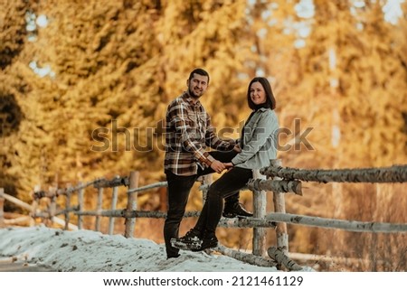 Photo of pretty adorable girlfriend and boyfriend dressed casually. A woman sitting on the edge of a fence. Selective focus. High quality photo
