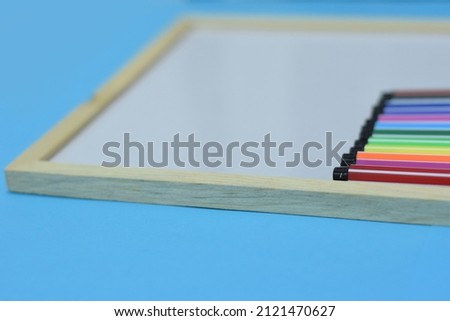 Selective Focus of A Set of Colourful Magic Ink Pens On A Wooden White Board Isolated with Blue Background 
