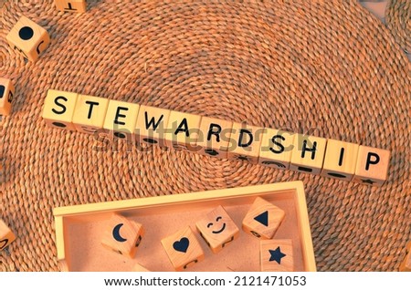 STEWARDSHIP word text from wooden cube block letters on braided rattan mats background. Stewardship is the office, duties, and obligations of a steward. Royalty-Free Stock Photo #2121471053