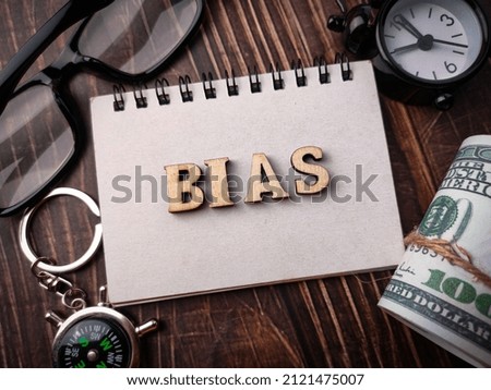 Top view compass,banknotes,glasses,clock and wooden word with text BIAS on a wooden background.