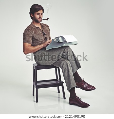 Who needs a desk anyway. Studio shot of a 70's style businessman sitting on a stool using a typewriter. Royalty-Free Stock Photo #2121490190