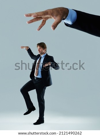 Just a puppet for the corporations. Shot of a businessman being made to move like a puppet by a hand hovering above him.