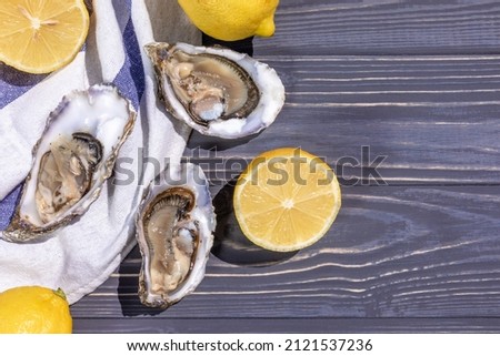 Open oysters with lemon on a beautiful blue plate, on a textured wooden background.