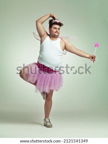 I do ballet. An overweight man comically dressed-up in a pink fairy costume doing ballet. Royalty-Free Stock Photo #2121541349