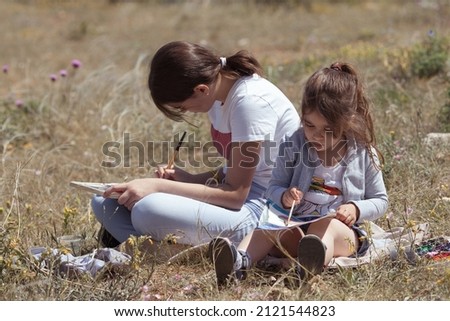 The girls draw in the park, plein air. Child learns to draw in nature