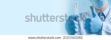 ?lose up of doctor's hands in medical gloves holding negative self testing COVID-19 Delta variant strain test and showing thumbs up gesture.The concept of medicine, convalescence. Banner, copy space