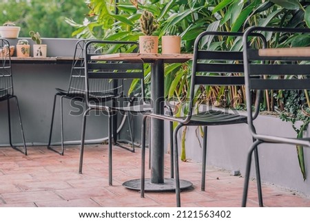 Cozy veranda balcony terrace open air tropical style cafe metal chair table furniture. Green nature leaves summer day. Modern decor interior warm atmosphere Relax Outdoor recreation dining garden area