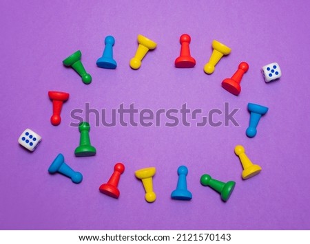 Game frame made of colored game chips and playing cubes laid out on a purple background: entertainment, games at home for the whole family, the concept of board games. Board game. Table games