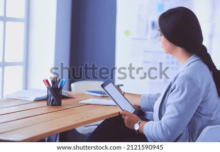 Pretty young female manager using modern digital tablet at office.