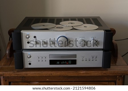 Compact Disc Player - a high quality Compact Disc (CD) player with a matching amplifier in brushed aluminum. Front view with assorted discs on top. CD drawer closed. Royalty-Free Stock Photo #2121594806