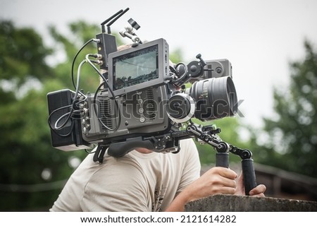 Behind the scene. Cameraman shooting the film scene with his camera on outdoor location