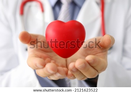 Doctor cardiologist holds small red heart closeup Royalty-Free Stock Photo #2121623522