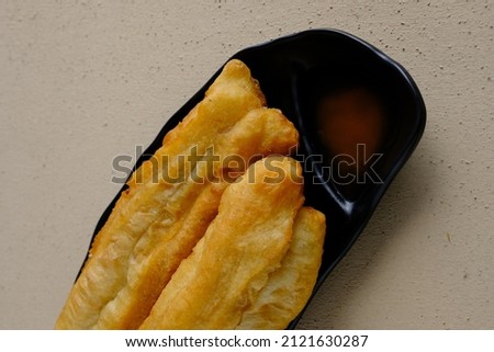 traditional Medan fried dough called Cakwe on a black plate on a textured grainy table and vintage backgorund