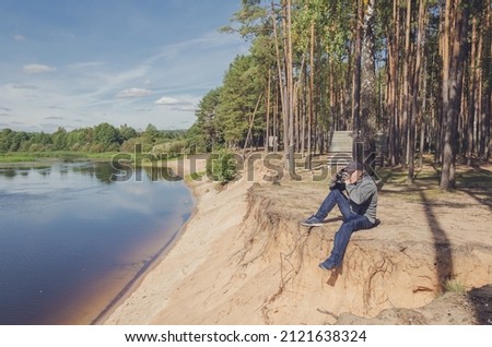 Photographer relaxes in nature near the river. Beautiful landscape outdoor recreation.