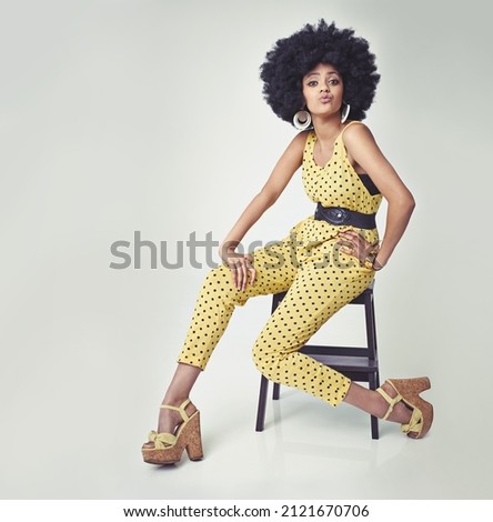 She's got va va voom. A young woman wearing a 70s retro jumpsuit while in the studio. Royalty-Free Stock Photo #2121670706