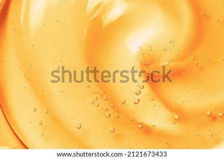 Orange gel texture background. Gold cosmetic transparent cream swirl with bubbles. Citrus fruit skincare product closeup