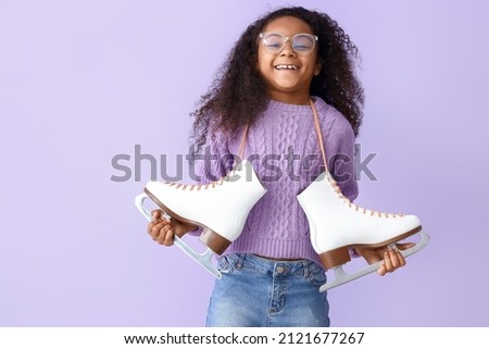 Little African-American girl in eyeglasses with ice skates on lilac background