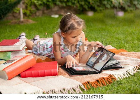 Little girl at park looking at family photo album