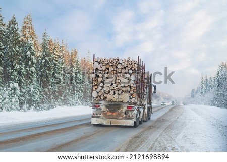 A logging truck carries lumber along a winter highway. Royalty-Free Stock Photo #2121698894