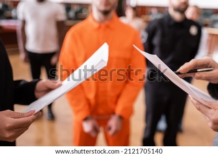 partial view of advocate and prosecutor with documents near accused man and jurors on blurred background Royalty-Free Stock Photo #2121705140