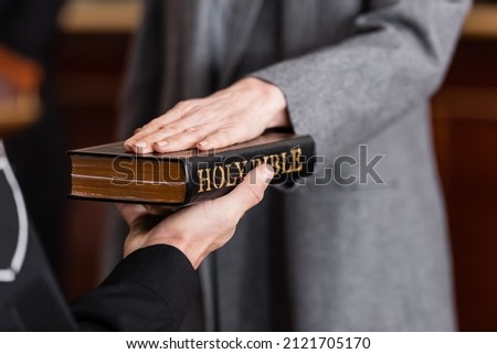 partial view of bailiff holding bible near woman giving swear in court Royalty-Free Stock Photo #2121705170