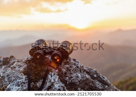 binoculars on top of rock mountain at sunset Royalty-Free Stock Photo #2121705530