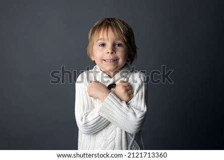 Cute little toddler boy, showing  I LOVE YOU gesture in sign language on gray background, isolated image, child showing hand sings 