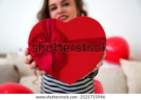 Close up of woman hold gift box red heart for Valentines Day.Delivery present.Suprise
