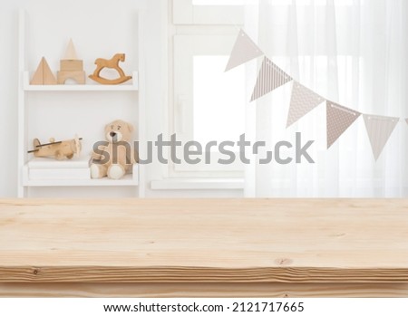 Wooden desk on blurred child room or kindergarten interior background Royalty-Free Stock Photo #2121717665