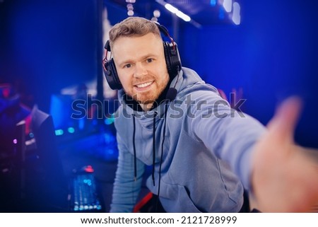 Streamer young man professional gamer playing online games computer with headphones make selfie photo, neon color.