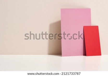 blank pink and red cardboard sheet of paper with shadow on white table. Template for flyer, announcement