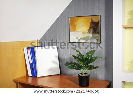 Part of room interior with documents, houseplant and painting on wall, copy space